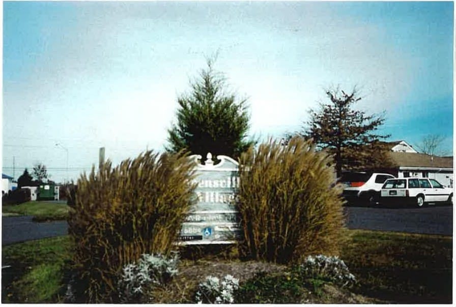The Stevensville Village Apartments entrance sign framed by ornamental grasses and flowers